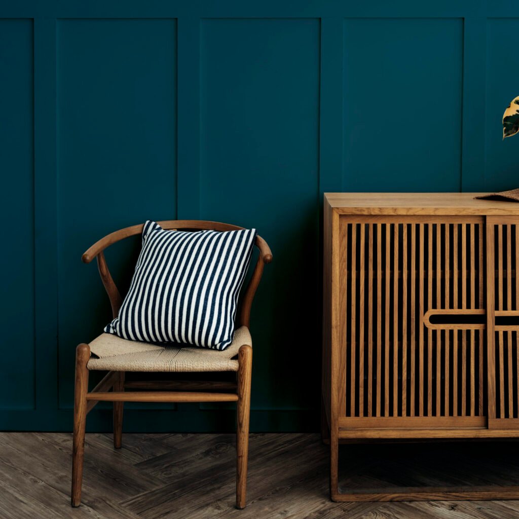 scandinavian vintage wood cabinet with chair by a dark blue wall